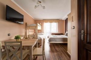 a room with a dining table and a room with beds at Willa Sichelscy - apartamenty i pokoje z aneksami kuchennymi - rabat 20 procent na Termy Szaflary oraz Gorący Potok oraz 15 procent rabatu na Bramę Gorce in Biały Dunajec