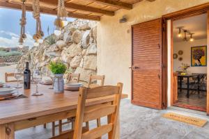 uma sala de jantar com uma mesa de madeira e uma parede de pedra em Sa Domo Isola Rossa em Trinità d'Agultu e Vignola