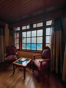 sala de estar con 2 sillas, mesa y ventana en Wingait Inn - Hotel Near The Mall Road, en Shimla