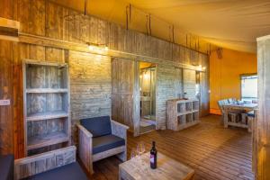 Habitación con paredes de madera y mesa con botella de vino. en Luxury Lodge Glamping en Palazzolo dello Stella
