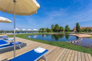 a large swimming pool with chairs and an umbrella at Luxury Lodge Glamping in Palazzolo dello Stella