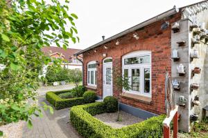 uma casa de tijolos com sebes à frente em Ferienwohnung Kaffeemühle em Flensburg