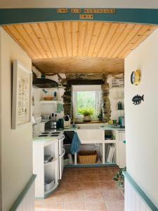 a kitchen with white cabinets and a wooden ceiling at The Old Boathouse at Bunbeg Harbour in Bunbeg