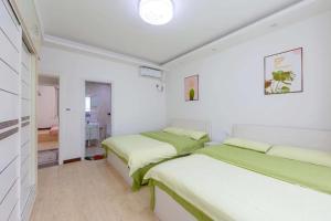 two beds in a room with white walls at Xi Valley Apartment in Zhangjiajie