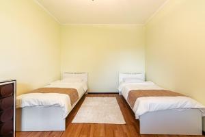 アルマトイにあるУютный дом в медеуском районеの白い壁とウッドフロアの客室で、ベッド2台が備わります。