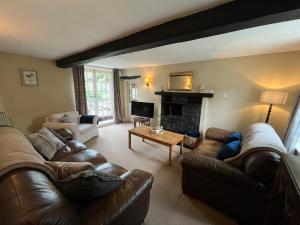 een woonkamer met lederen meubels en een open haard bij Wensleydale Stone Cottage in Hunton