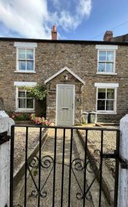 a brick house with a grey door in front of it at Wensleydale Stone Cottage in Hunton
