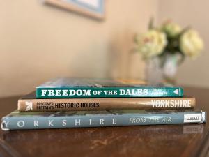 drie boeken bovenop elkaar op een tafel bij Wensleydale Stone Cottage in Hunton