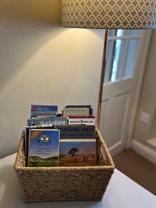 a basket of books sitting on a table next to a lamp at Wensleydale Stone Cottage in Hunton