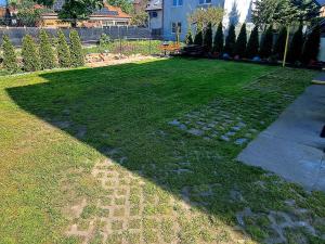 a backyard with a lawn with rocks and a sidewalk at Puszek in Ustka