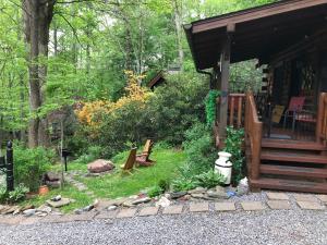 un patio trasero con una cabaña con un banco y árboles en Little Wolf Cabin, en Maggie Valley