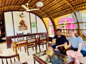 dos personas sentadas en un sofá en un restaurante en Thara's Houseboat, en Alleppey