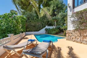 a swimming pool with two lounge chairs next to a house at Villa Maria in Jávea