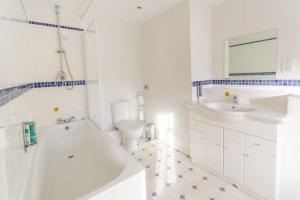 a white bathroom with a tub and a toilet and a sink at Pettifers Freehouse Hotel in Crudwell +63 photos