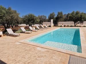 Trulli Tramontana - private pool في أوستوني: مسبح مع كراسي جلوس بجانب منتجع