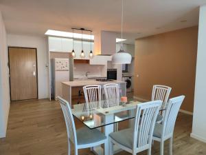 cocina y comedor con mesa de cristal y sillas en Isa Charme Home, en Praia