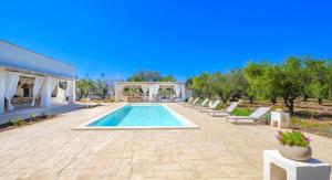 Trulli Tramontana - private pool في أوستوني: مسبح مع كراسي جلوس ومنزل