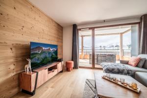 a living room with a flat screen tv on a wooden wall at Apartment Epicea Alpe d'Huez - by EMERALD STAY in L'Alpe-d'Huez