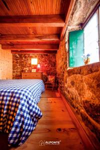 um quarto com uma cama numa parede de pedra em Refugio dos Cartolas em São Mamede