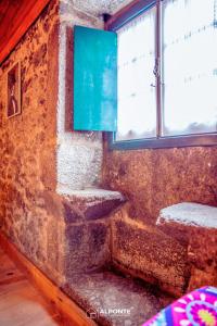 una camera con un muro in pietra con due finestre di Refugio dos Cartolas By ALPONTE a São Mamede