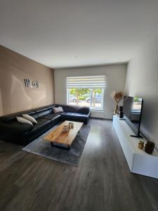 a living room with a black couch and a table at Casa Cinco in Valkenburg