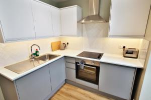 een kleine keuken met witte kasten en een wastafel bij Peaceful Garden Apartment on Roman Road in Londen