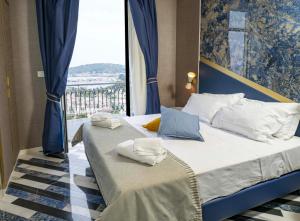 a bed with blue and white pillows and a window at Hotel Cala Moresca in Bacoli