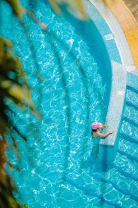 a woman in a swimming pool with a pink umbrella at Calheta Beach - All-inclusive - Savoy Signature in Calheta