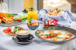 una mesa con platos de comida y una taza de café en Sekli Panzió, en Balatonlelle