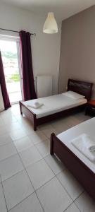 two beds in a room with a window at KANALI HOLIDAYS APARTMENT in Kanali