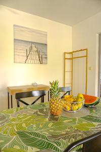 een tafel met een ananas en een fruitschaal erop bij T2 Climatisé avec Jacuzzi à 5 minutes des plages in Les Trois-Îlets