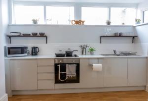 a white kitchen with a stove and a microwave at Fulwood Heights Apartments in Preston