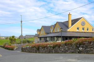 una casa gialla con un muro di pietra accanto a una strada di Doolin Inn a Doolin