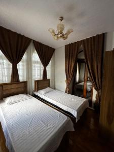 two beds in a bedroom with a chandelier at Zaynullo Guest House in Bukhara