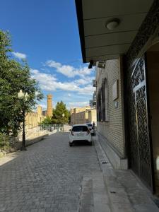 a white car parked on a street next to a building at Zaynullo Guest House in Bukhara