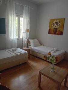 a bedroom with two beds and a table with a vase of flowers at Mary's Place Stalis in Stalida