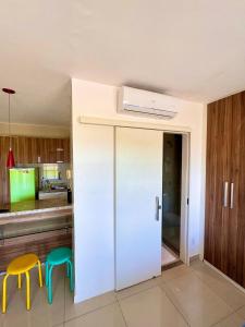 a kitchen with a white door and two stools at VG FUN Praia do Futuro Pé na Areia ap 311 IMOB TEMPORADA in Fortaleza