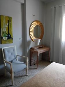 a bedroom with a chair and a table with a mirror at Mary's Place Stalis in Stalida