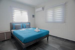 a bedroom with a bed with a blue blanket and two windows at Casa Lima- Lovely Home Among All The Hotspots in Noord