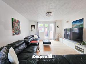 un soggiorno con divano in pelle nera e TV a schermo piatto di Inviting & Spacious 6bdr Home With Free Parking! a Manchester