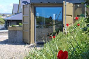 a house with a glass door and red flowers at Doolin Inn in Doolin