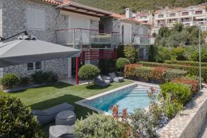 a backyard with a swimming pool and an umbrella at Tyros Boutique Houses Villas in Tiros