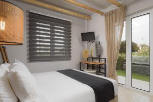 a bedroom with a white bed and a window at Tyros Boutique Houses Villas in Tiros