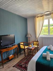 Cette chambre comprend un lit, une télévision et une table. dans l'établissement Domaine Bassy, à Saint-Gengoux-de-Scissé