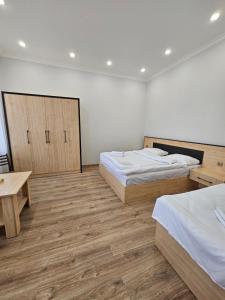 two beds in a room with wooden floors at Shahumyan 98 Guest house in Gyumri