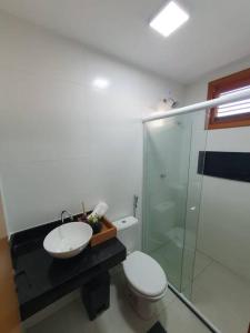 a bathroom with a sink and a toilet and a glass shower at Casa Icaria Atins MA in Atins