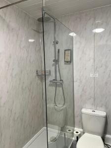 a bathroom with a glass shower with a toilet at MK Hotel in Milton Keynes