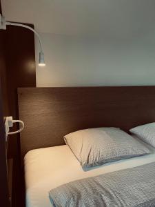 uma cama com uma cabeceira de madeira ao lado de uma cama com um candeeiro em Town hostel em Pec