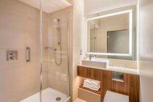 a bathroom with a shower and a toilet and a sink at Courtyard by Marriott Edinburgh in Edinburgh
