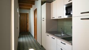 een keuken met witte kasten en een wastafel bij Penthouse Rooms Marigliano - Eleganza sopra le nuvole in Marigliano
